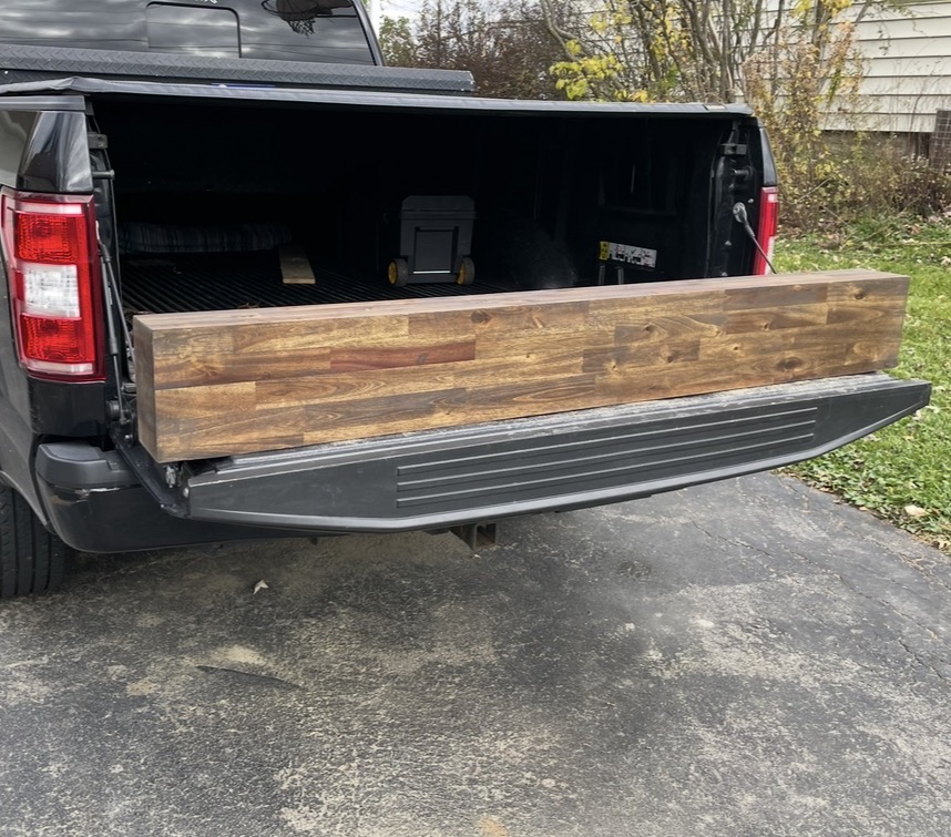 Long stained wood piece resting on a truck tailgate